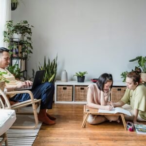 A family engaged in home study with dad on a laptop and mom helping daughter with homework.