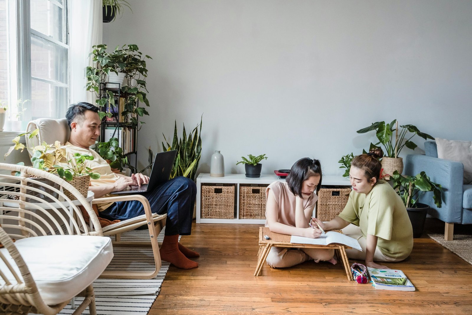 A family engaged in home study with dad on a laptop and mom helping daughter with homework.