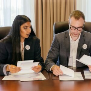 Two professionals in a meeting reviewing documents at a conference table.