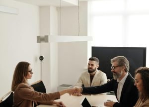 pexels-photo-4342493-4342493 Business professionals engaging in a handshake across a conference table, signifying successful collaboration.